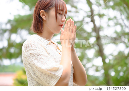 新緑の中で静かに祈る女性 134527890
