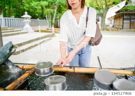 神社で柄杓を使い手を清める女性 134527906