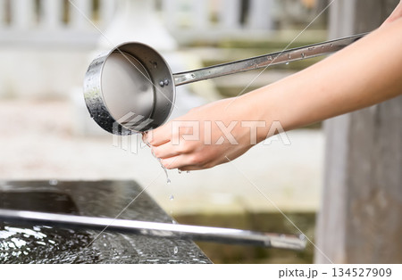 手水舎で柄杓を使い手を清める女性 手水舎で柄杓を使い手を清める女性 134527909