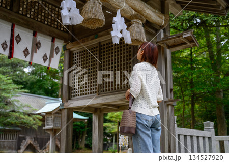 神社で注連縄を見上げる女性の後ろ姿 134527920