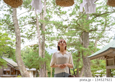 神社で注連縄を見上げる女性 134527921