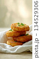 Stack of golden potato pancakes garnished with fresh dill on a soft linen napkin 134529306