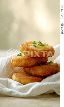 Stack of golden potato pancakes garnished with fresh dill on a soft linen napkin 134529306