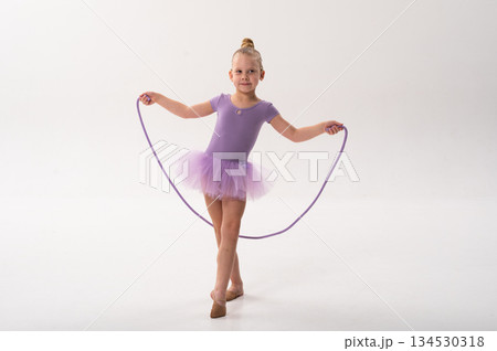 Ballerina girl with hearing implant holding purple rope. Copy space. Expression of inclusion, grace, and courage through sound restoration and art. Ballerina girl with hearing implant holding purple rope. Copy space. Expression of inclusion, grace, and courage through sound restoration and art. 134530318