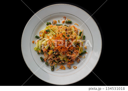 Overhead shot of Lombok traditional spicy mixed vegetable salad (Plecing Sayur or Urap) on white plate against black background. Overhead shot of Lombok traditional spicy mixed vegetable salad (Plecing Sayur or Urap) on white plate against black background. 134531018
