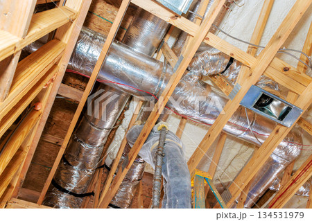Metal ducts are installed within wooden framing at construction site, HVAC setup process 134531979