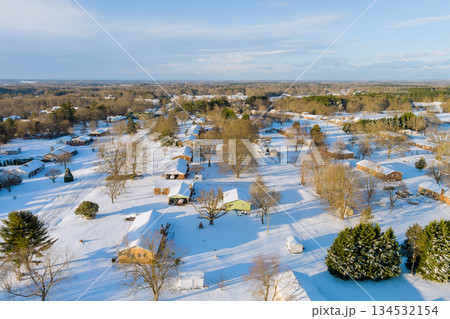 Snow covers houses trees in American village peaceful suburban area, creating serene winter scene Snow covers houses trees in American village peaceful suburban area, creating serene winter scene 134532154