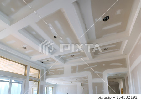 Ceiling with coffered design is in progress, drywall work lighting fixtures in new home. Ceiling with coffered design is in progress, drywall work lighting fixtures in new home. 134532192