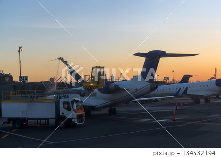 Refueling action takes place as evening light casts warm glow over busy airport terminal. Refueling action takes place as evening light casts warm glow over busy airport terminal. 134532194