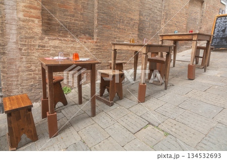 Empty restaurant tables in old town street. Calm European dining scene Empty restaurant tables in old town street. Calm European dining scene 134532693