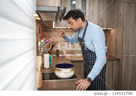 Man Standing in Kitchen Preparing Food 134532790