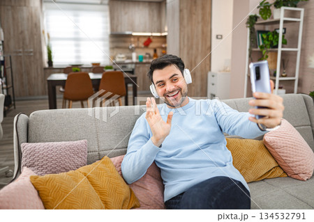 Man with wireless headphones talking on a video call at home Man with wireless headphones talking on a video call at home 134532791