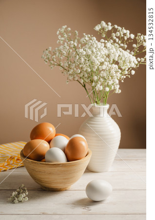 Easter eggs background. White eggs in wooden bowl and gypsophila flowers in a vase. Spring holiday 134532815