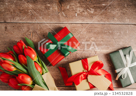 Mothers' day. Red tulips with gift boxes. Easter holiday. Wooden background, copy space. 134532828