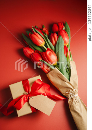 Mothers' day. Red tulips with gift box. Easter holiday. Red background, copy space. 134532844