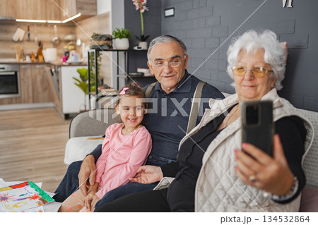 Grandparents and granddaughter smile in living room Grandparents and granddaughter smile in living room 134532864