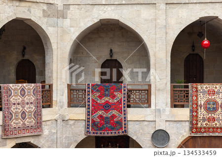 Historic stone arches frame a sunny courtyard, with vibrant Persian rugs Historic stone arches frame a sunny courtyard, with vibrant Persian rugs 134533459