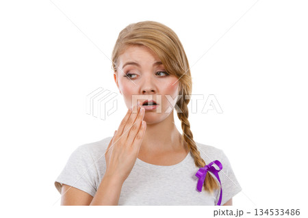 Upset teenage woman with hand close to lips Upset teenage woman with hand close to lips 134533486