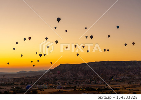 Hot air balloon flying over rocky landscape at sunrise in Cappadocia. Turkey Hot air balloon flying over rocky landscape at sunrise in Cappadocia. Turkey 134533828
