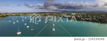 Aerial panorama of Grand Baie Mauritius with turquoise lagoon anchored catamarans and town coastline under dramatic clouds Aerial panorama of Grand Baie Mauritius with turquoise lagoon anchored catamarans and town coastline under dramatic clouds 134534349