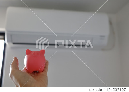 エアコンと豚の貯金箱を使った節電や電気代節約のイメージ。 134537197