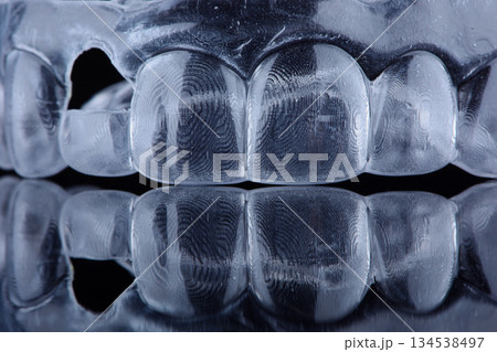 Printed transparent dental cap made of polymer on a light colorful background. Dental splint against bruxism. 134538497