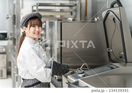 厨房機器を使う女性調理スタッフ 134539391