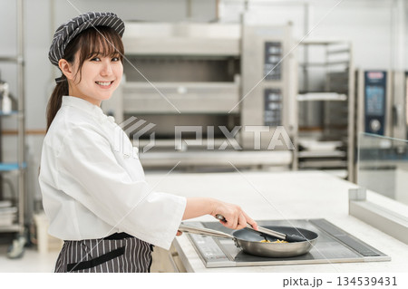 IHコンロでフライパン調理するシェフの女性 IHコンロでフライパン調理するシェフの女性 134539431