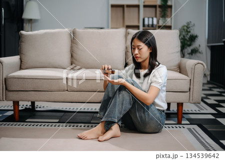 Asian woman sit Depression Dark haired pensive glance Standing by window and anxiety Copy space with a blanket on a sofa. Asian woman sit Depression Dark haired pensive glance Standing by window and anxiety Copy space with a blanket on a sofa. 134539642