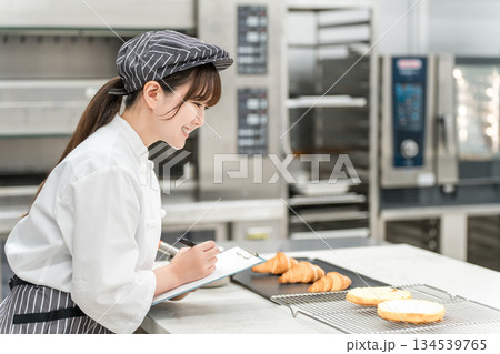 厨房でパンの商品チェック,研究,商品開発,衛生管理,品質管理をする女性スタッフ 134539765