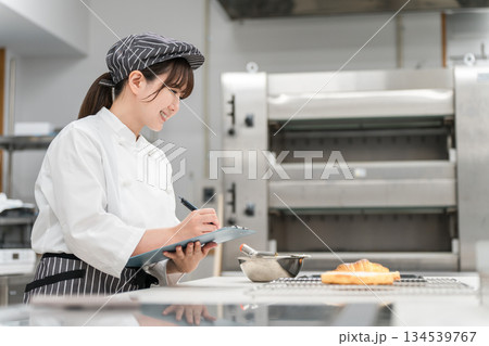 厨房でパンの商品チェック,研究,商品開発,衛生管理,品質管理をする女性スタッフ 134539767