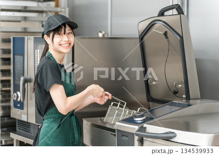 厨房でフライヤーを使う調理スタッフの女性 134539933