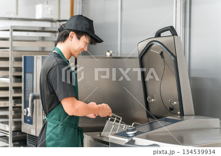 厨房でフライヤーを使う調理スタッフの男性 134539934