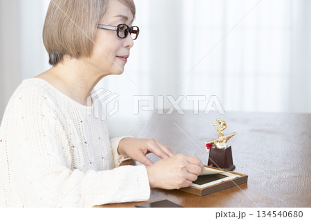 リビングで写真を額に入れて飾るシニア女性 134540680