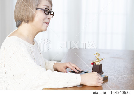 リビングで写真を額に入れて飾るシニア女性 リビングで写真を額に入れて飾るシニア女性 134540683