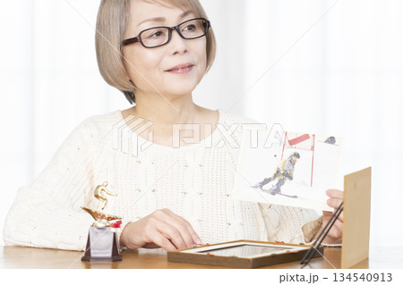 リビングで写真を額に入れて飾るシニア女性 134540913