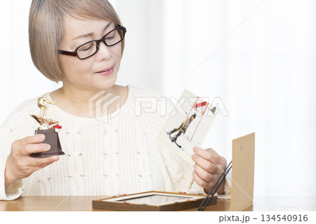 リビングで写真を額に入れて飾るシニア女性 リビングで写真を額に入れて飾るシニア女性 134540916