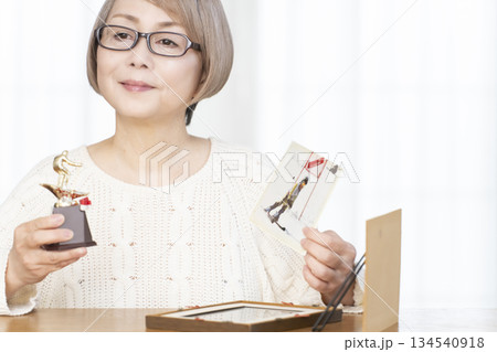 リビングで写真を額に入れて飾るシニア女性 134540918