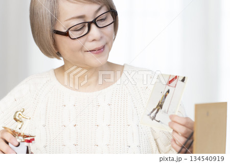リビングで写真を額に入れて飾るシニア女性 134540919