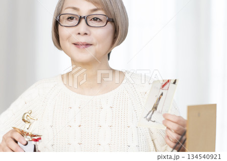 リビングで写真を額に入れて飾るシニア女性 134540921