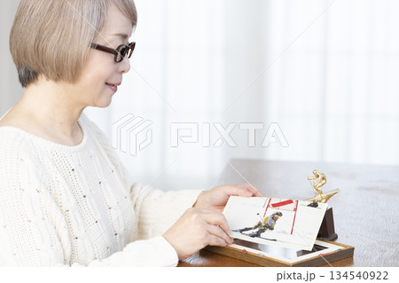 リビングで写真を額に入れて飾るシニア女性 134540922