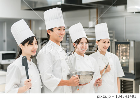 厨房・キッチンに立つコックコート姿の調理師・シェフ・コックの男女 厨房・キッチンに立つコックコート姿の調理師・シェフ・コックの男女 134541493