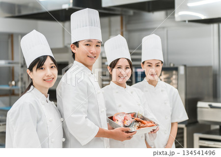 厨房・キッチンに立つコックコート姿の調理師・シェフ・コックの男女 134541496
