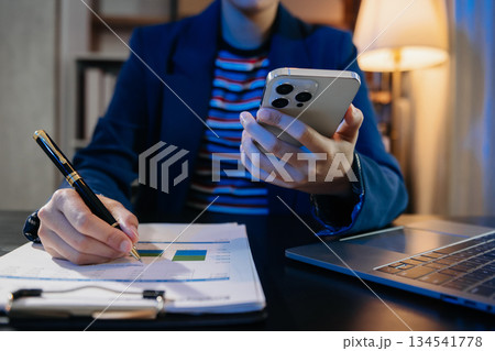 Women counting coins on calculator taking from the piggy bank. hand holding pen working on calculator at home office. 134541778