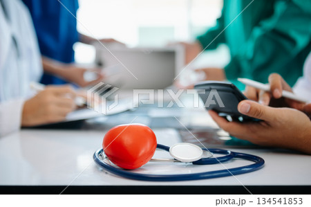 Medical team having a meeting with doctors in white lab coats and surgical scrubs seated at a table discussing a patients working online using computers Medical team having a meeting with doctors in white lab coats and surgical scrubs seated at a table discussing a patients working online using computers 134541853