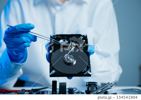 Hard disk drive on the technician's desk and a computer motherboard as a component. the concept of data, hardware, and information technology. 134541904