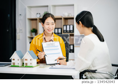 balancing the property sector The real estate agent is explaining the house style to see the house design and the purchase agreement. 134542043