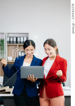 Two business workers talking on the smartphone and using laptop at office Two business workers talking on the smartphone and using laptop at office 134542376