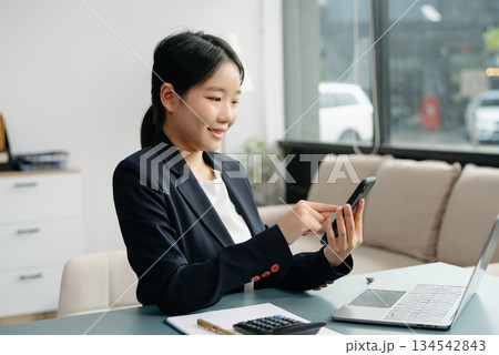 Young beautiful woman typing on tablet and laptop while sitting at the working white table 134542843