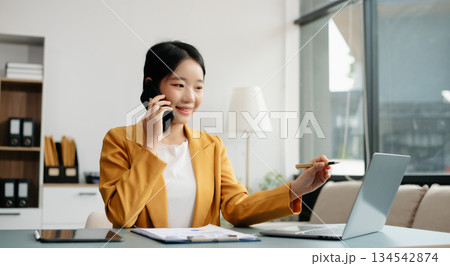 Confident Asian woman with a smile standing holding notepad and tablet at the office. Confident Asian woman with a smile standing holding notepad and tablet at the office. 134542874